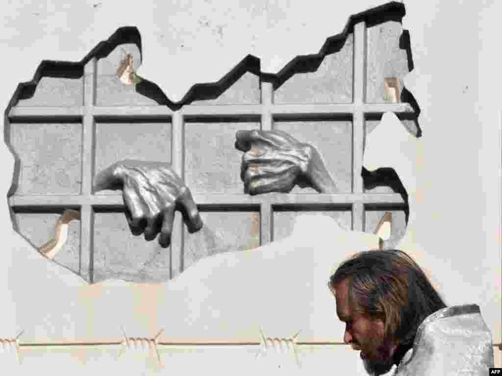 Seorang pendeta Kristen Ortodoks berdiri di dekat tugu peringatan korban di era penindasan Uni Soviet di kota Stavropol, Rusia selatan. 