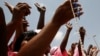 FILE - Women from a Catholic society wave rosary beads as they watch the convoy of Pope Benedict XVI pass on the way to a meeting between the pope and Cameroonian bishops, in Yaounde, March 18, 2009. 