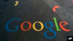 FILE - The Google logo is printed on the carpet of the Google cultural institute in Paris, Dec. 10, 2013.