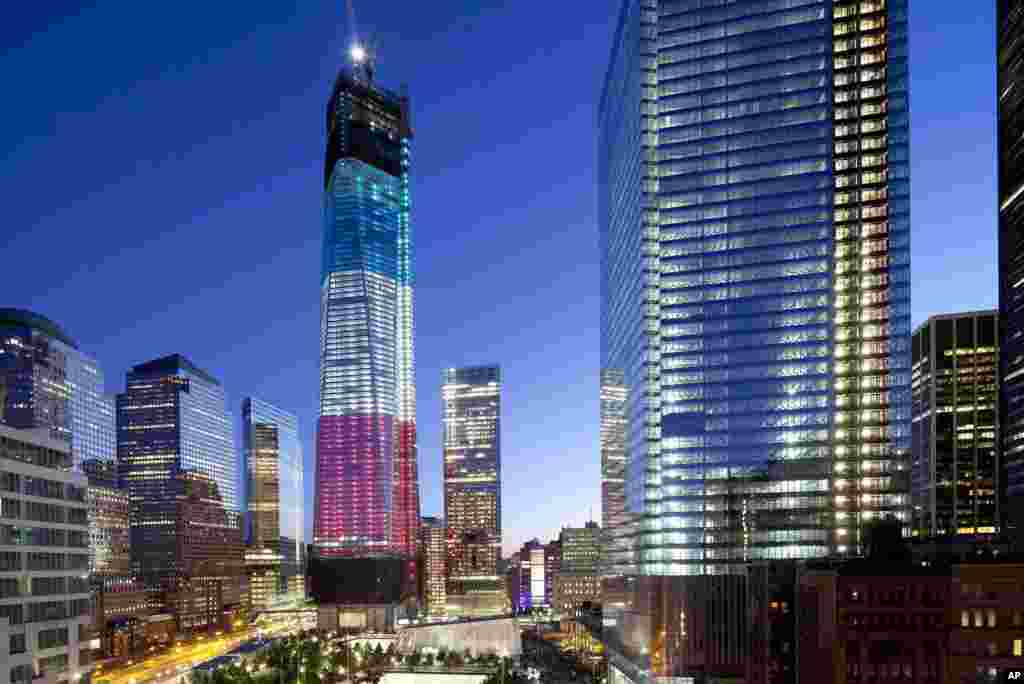 Menara yang dikenal sebagai 1 World Trade Center (kiri), Monumen Nasional 11 September (kiri bawah) dan 4 World Trade Center (kanan) bermandikan cahaya lampu, New York (11/9).
