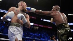 Floyd Mayweather Jr. jabs Conor McGregor in a super welterweight boxing match, Aug. 26, 2017, in Las Vegas.