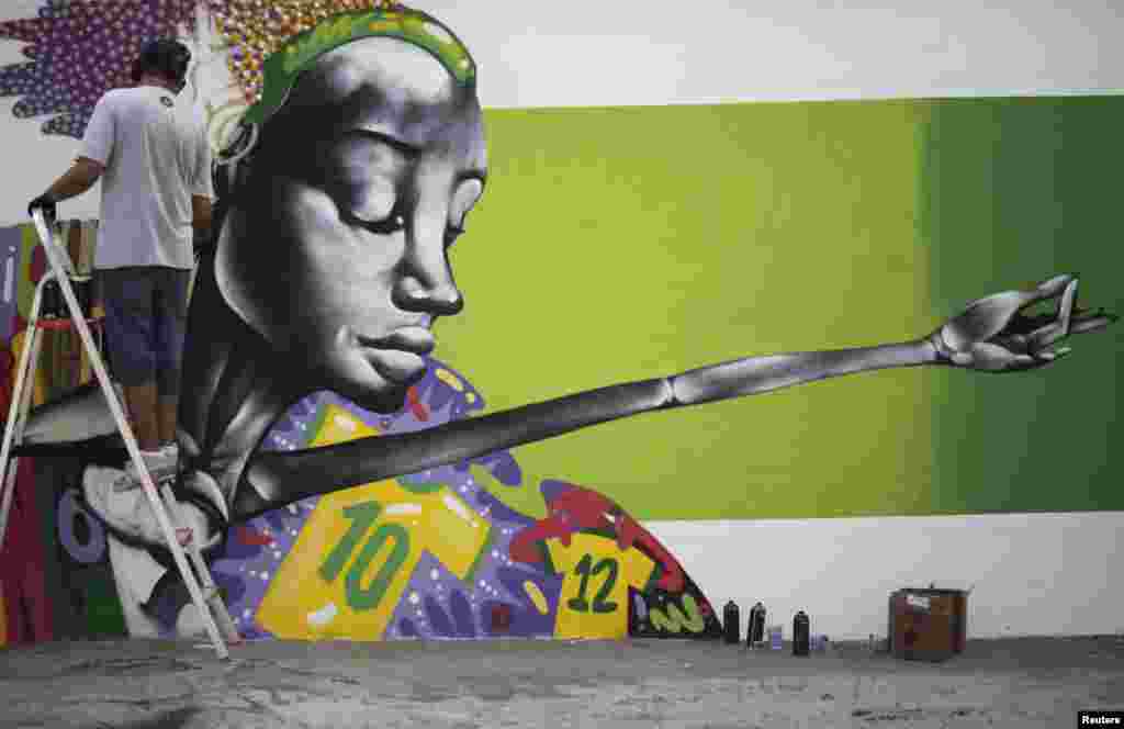 Seniman grafiti Barba bekerja pada mural dalam rangka perayaan&nbsp; kejuaraan sepak bola Piala Dunia 2014 di Rio de Janeiro, Brasil. Mural itu akan menjadi bagian dari sebuah kontes yang diselenggarakan oleh balai kota di kota itu. &nbsp;