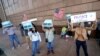 FILE - Campaign signs are posted near the Supervisor of Elections Office polling station while people line up for early voting in Pinellas County ahead of the election in Largo, Florida., Oct. 21, 2020. 