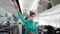 A flight attendant gives instructions to passengers on a plane in Ho Chi Minh City, Vietnam, March 16, 2020. 