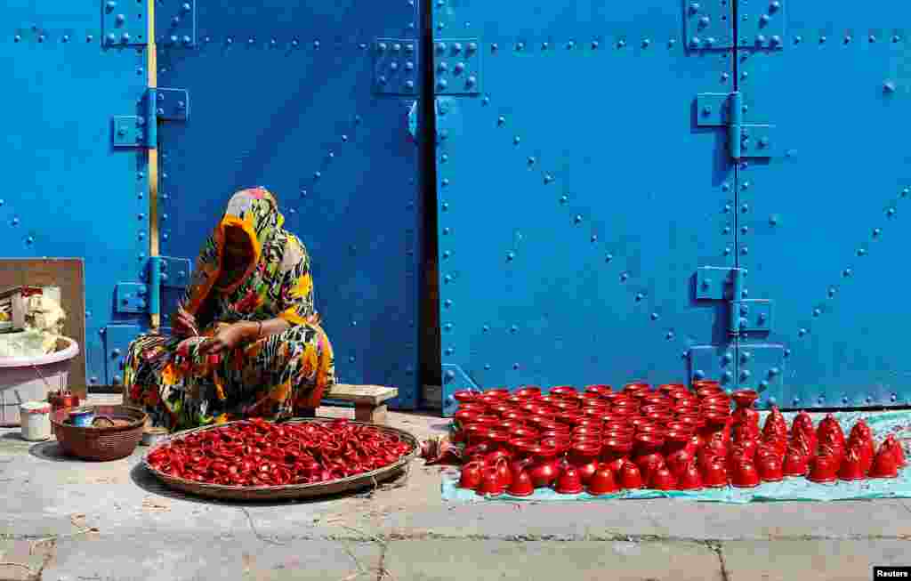 Seorang perempuan mengecat tempat lampu yang dipakai untuk dekorasi festival Hindu Diwali, atau festival cahaya di Kolkata, India.