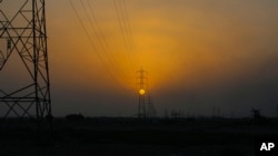 خۆر ئاوابوون لە پشت هێڵەکانی گواستنەوەی وزەی کارەبا لە ئێرانەوە بۆ عێراق لە شاری بەسرەی عێراق، 29ی حەوتی 2021