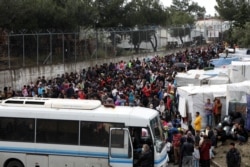 FILE - Migrants from the Moria camp wait to board busses to the port from where they will be transferred to the mainland as a precaution against the spread of the coronavirus disease (COVID-19) outbreak, on the island of Lesbos, Greece, May 3, 2020.