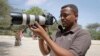 FILE - Somali journalist Mohamed Mohamud holds his camera in the Medina hospital compound in Mogadishu, Somalia, Jan. 18, 2013. Mohamud was killed on the job in 2013.
