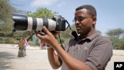 FILE - Somali journalist Mohamed Mohamud holds his camera in the Medina hospital compound in Mogadishu, Somalia, Jan. 18, 2013. Mohamud was killed on the job in 2013.