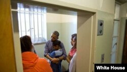 Photo d’archives : Le président Barack Obama et la Première Dame Michelle, avec leurs filles Sasha et Malia, dans la cellule de l'ancien président sud-africain Nelson Mandela, écoutant l’ancien prisonnier Ahmed Kathrada, lors d’une visite à la prison de Robben Island au Cap, en Afrique du Sud, 30 juin 2013.