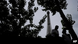  የ2024 የፓሪስ ኦሎምፒክ የመክፈቻ ሥነ ሥርዓትን ከአይፍል ታወር ፊት ለፊት የሚጠባበቁ ጥንዶች፡፡ ፓሪስ፣ ፈረንሳይ ፣ ሐምሌ 19 ቀን 2016 ዓ.ም. (AP Photo/Alessandra Tarantino)