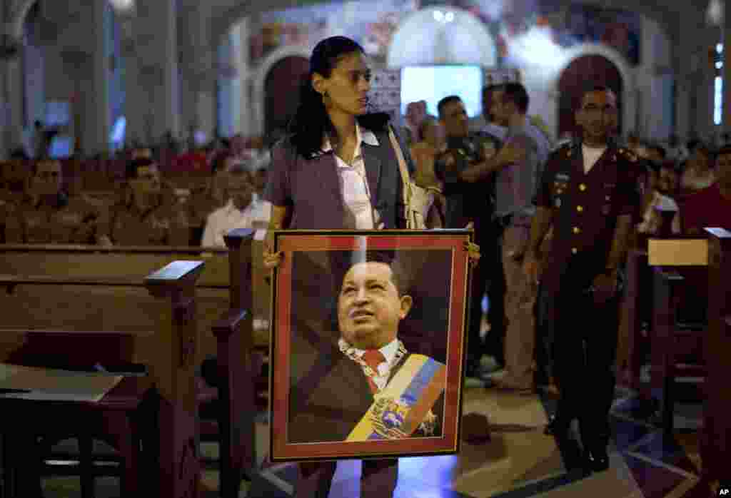 Seorang perempuan membawa foto Chavez sebelum misa untuk mendoakannya di Havana, Kuba, 13 Desember 2012.