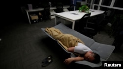 FILE - A worker sleeps in the office after finishing work early morning, in Beijing, China, April 27, 2016. (REUTERS/Jason Lee)