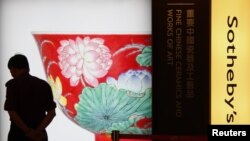 A security guard walks past a poster of a ruby-ground falangcai "Double-Lotus" bowl from China's Kangxi period, during Sotheby's preview in Hong Kong, April 2, 2013.