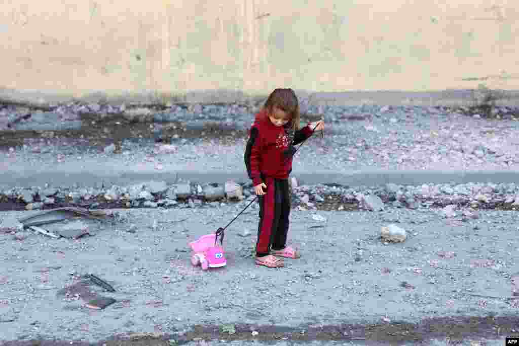 A Palestinian girl pull on a her toy on a debris-filled street in Jabalia in the northern Gaza Strip, amid the ongoing war between Israel and the Palestinian Hamas movement.