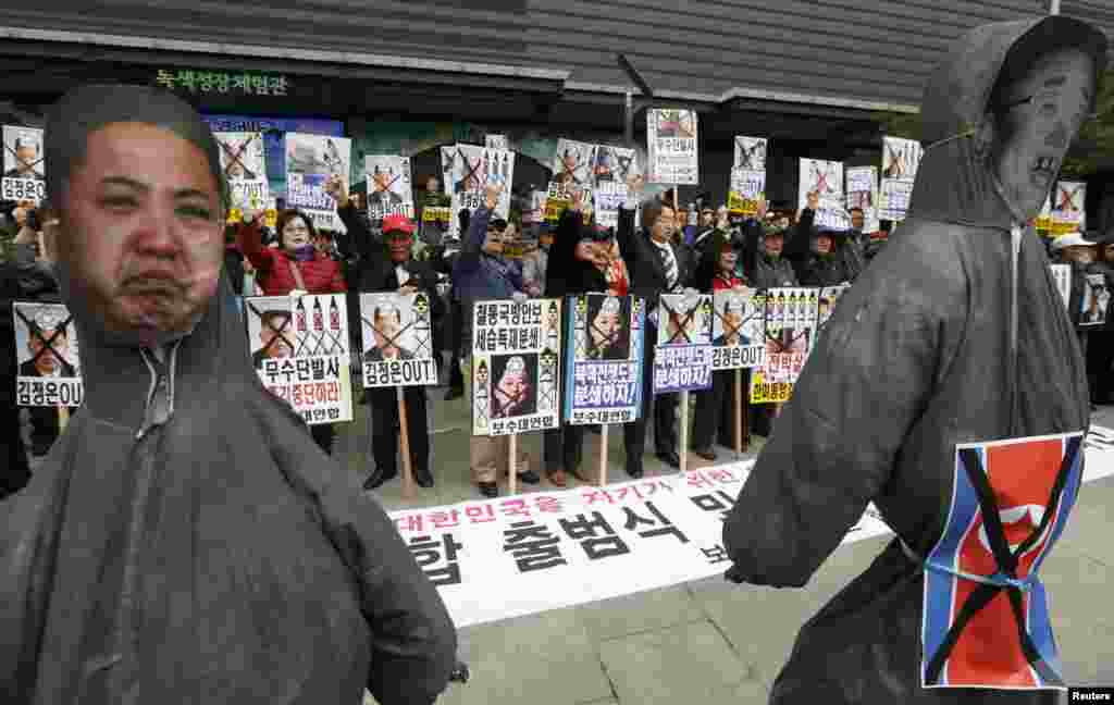 2013年4月15日，反对朝鲜的抗议者在韩国首都首尔市中心举着金正恩和其父金正日的画像呼喊口号。