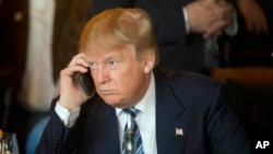 FILE - Republican presidential candidate Donald Trump listens to his mobile phone during a lunch stop in North Charleston, South Carolina, Feb. 18, 2016.