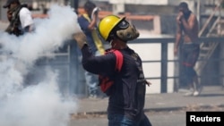 Učesnik protesta u Karakasu baca suzavac tokom demonstracija protiv aktuelnog predsjednika Nicolasa Madura (Foto: Reuters) 