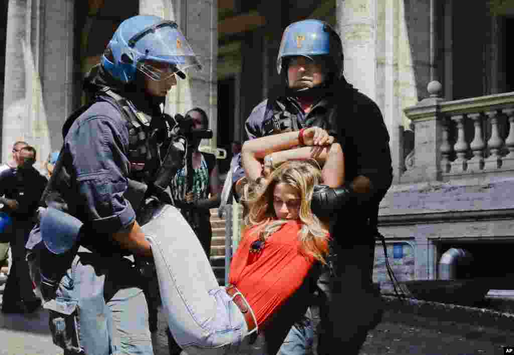 A protester is dragged away by Italian police outside the Ministry of Transport in Rome, Italy. Dozens of protesters chained themselves to the steps in a demonstration against the government&#39;s hardline immigration policy.