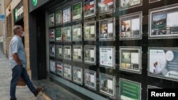 A man wearing a face mask looks at the window of Don Piso real estate agency office during the coronavirus disease (COVID-19) outbreak in El Masnou, north to Barcelona, Spain, May 19, 2020.