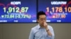 A currency trader walks by the screens showing the Korea Composite Stock Price Index (KOSPI), left, and the foreign exchange rate between U.S. Dollar and South Korean Won at the foreign exchange dealing room in Seoul, South Korea, June 24, 2016. 