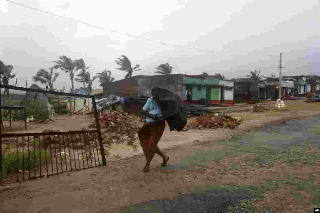 A woman walks towards shelter as heavy rain and wind gusts rip through the Bay of Bengal coast at Gopalpur, Orissa, Oct. 12, 2014.