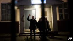 Pemimpin oposisi dan kandidat presiden Rusia, Alexei Navalny (kiri) melambai kepada pendukungnya setelah keluar dari kantor polisi di Moskow hari Jumat (29/9).
