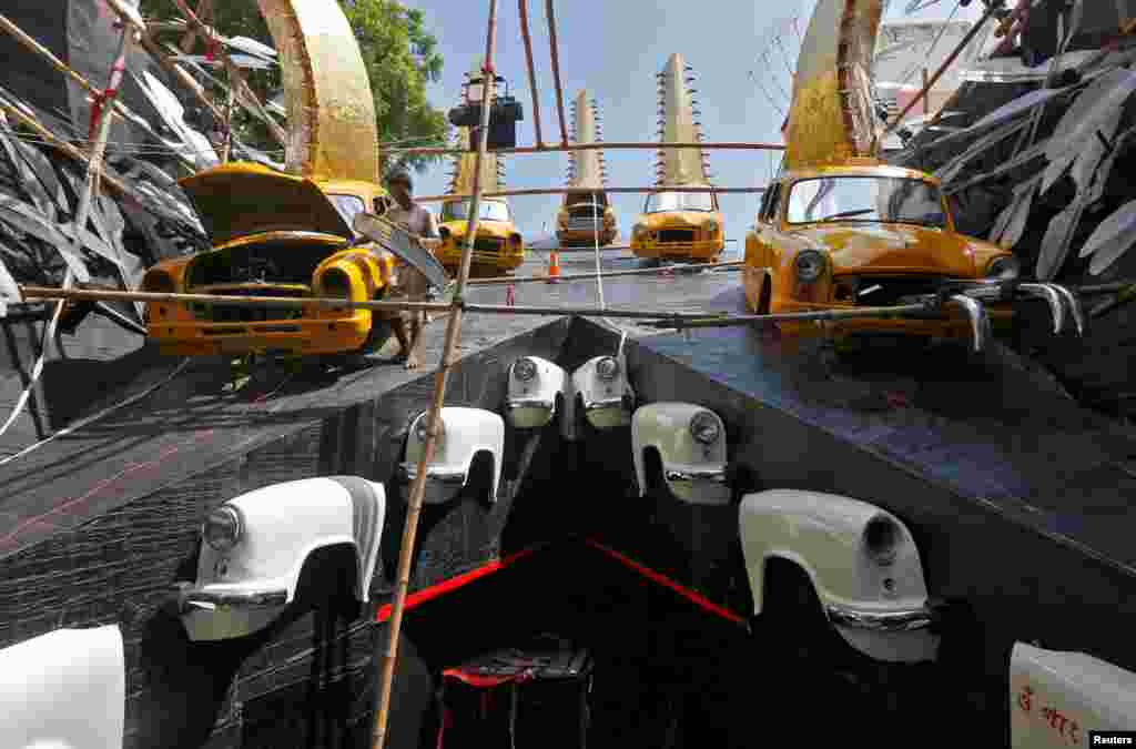 Seorang artisan mempersiapkan taksi Ambassador yang menjadi hiasan untuk festival Hindu Durga Puja, di Kolkata, India.&nbsp;(Reuters/Rupak De Chowdhuri)
