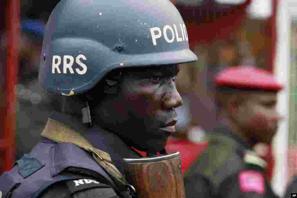 A police officer stand guards during a demonstration calling on government to rescue kidnapped school girls of a government secondary school Chibok, during workers day celebration in Lagos, Nigeria. Thursday, May, 1. 2014, Scores of girls and young women