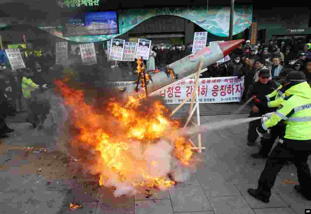 South Korean protesters burn a mock rocket as police officers spray fire extinguishers during a rally denouncing North Korea's rocket launch, Seoul, South Korea, December 12, 2012.