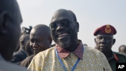 Ramadan Hassan Lako, à la tête d'une délégation de l'opposition armée du Sud-Soudan, sourit à un membre du gouvernement à l'arrivée à la capitale du pays Juba après la deuxième année de l'exil, 21 décembre 2015. 