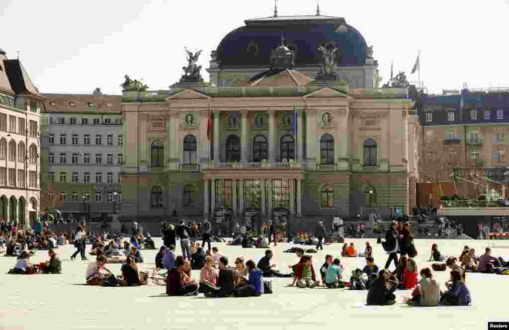 Warga Swiss menikmati cuaca hangat di Lapangan Sechselaeutenplatz di depan gedung opera di kota Zurich.&nbsp;