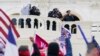 FILE - Supporters loyal to then-President Donald Trump challenge authorities before successfully breaching the Capitol building during a riot on its grounds, Jan. 6, 2021. Rioters tried to overturn America's presidential election, undercutting the nation'