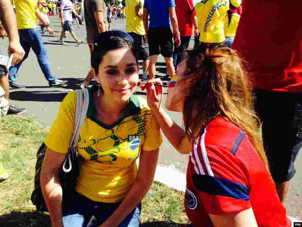 Seorang penggemar Piala Dunia mengecat wajahnya di luar stadion di Brasilia, 19 Juni 2014. (Nicolas Pinault/VOA)