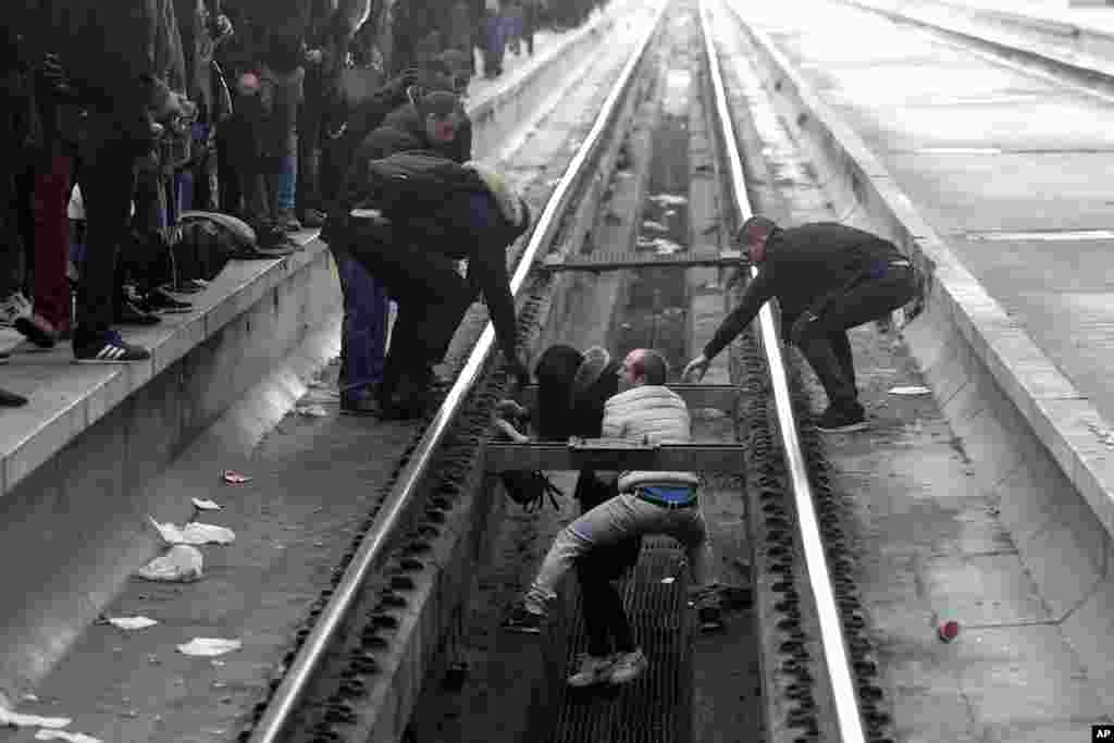 អ្នកដំណើរ​ជួយ​ស្រ្តី​ម្នាក់​ដែល​ធ្លាក់​ពី​ចំណត​ខណ​ដែល​នាង​ព្យាយាម​ឆ្លងកាត់​ស្ថានីយ៍​រថភ្លើង​ Gare de Lyon​ក្នុង​ទីក្រុង​ប៉ារីស​ អំឡុង​បាតុកម្ម​សហជីព​កម្មករ។