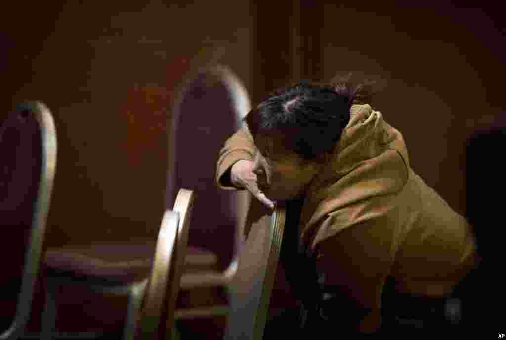 马航失联370航班乘客的家属3月13日在北京的一个旅馆房间里看电视，等待最新消息