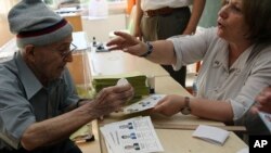 A polling station official checks the documents of an elderly voter as he waits to cast his vote for the Turkey's presidential election in Ankara, Aug. 10, 2014.