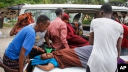 Medical workers and other Somalis help a civilian woman, who was wounded when a powerful car bomb blew off the security gates to the Elite Hotel, as she arrives at a hospital in Mogadishu, Somalia, Aug. 16, 2020. 