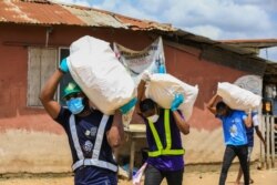 FILE - Volunteers carry sacks filled with food to distribute to vulnerable residents, during a lockdown by the authorities, part of the effort to limit the spread of COVID-19, in Lagos, Nigeria, April 9, 2020.