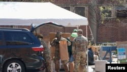 疫情期间，美国陆军国民警卫队员在纽约市曼哈顿哈莱姆区向民众分发由多家市政府机构提供的免费食物。(2020年4月15日)