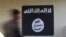  FILE - A soldier walks past a black flag commonly used by Islamic State militants. 