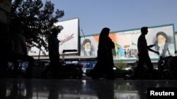 Ljudi prolaze pored murala koji prikazuje pokojnog vođu Islamske revolucije ajatolaha Ruholaha Homeinija i iranskog vrhovnog vođu ajatolaha Alija Hameneija na zgradi u ulici u Teheranu, Iran, 7. oktobra 2024. (Majid Asgaripour/WANA preko Reutersa)