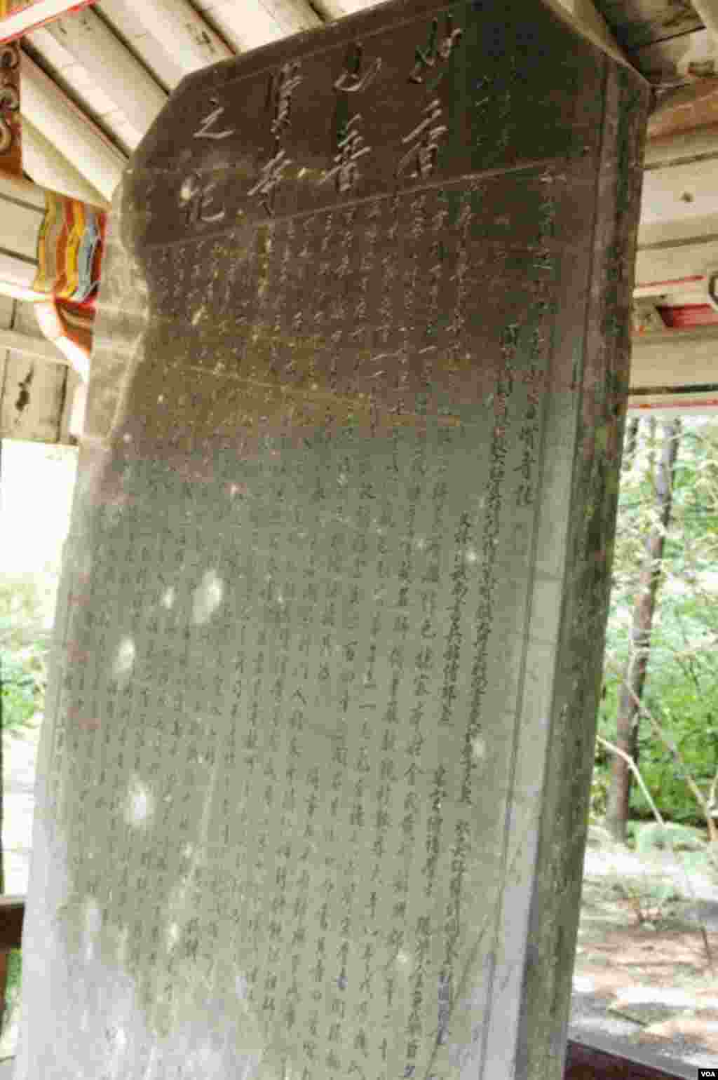 Pemandu wisata mengklaim bahwa bekas peluru di prasasti kuno yang ada di Hyangsan, Korea Utara, ini berasal dari pesawat AS selama Perang Korea (24/7). (VOA/Steve Herman)