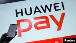 华为公司一名工作人员在2019年1月24日北京举行的华为5G产品发布会上显示其手机支付系统。