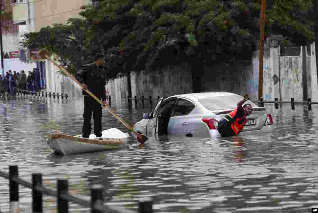 Tim penyelamat Palestina membantu menarik sebuah mobil yang terjebak banjir di kota Gaza.