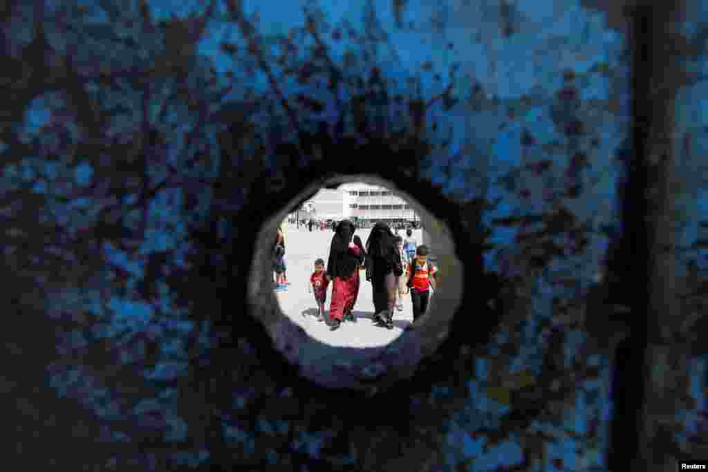 Anak-anak pengungsi usia sekolah berjalan bersama ibu-ibu mereka di hari pertama tahun ajaran baru di sekolah-sekolah yang dikelola UNRWA di kamp pengungsi Palestina al Wehdat, Amman, Yordania.