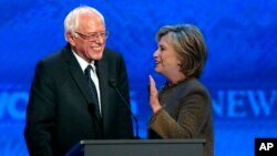 Bernie Sanders, à gauche, s'entretient avec Hillary Clinton lors du débat des candidats démocartes pour les primaires de leur parti, à l'institut Saint Anselm à Manchester, N.H., 19 décembre 2015.