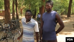Eric Aniva (left) in a striped gold shirt smokes a cigarette before sentencing started on Tuesday at Nsanje magistrate court. (L. Masina for VOA)