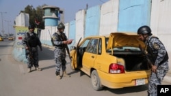 Polisi federal Irak memeriksa sebuah mobil di pos pemeriksaan di Baghdad, Irak (23/1). (AP/Karim Kadim)