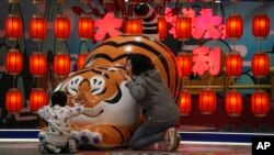 北京一家商场设立的卡通老虎迎接虎年春节，一对母子围着卡通老虎做游戏。（2022年1月9日）